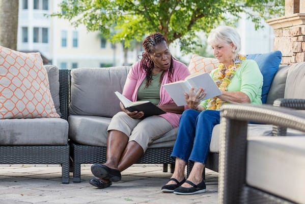 Two residents reading books outdoors on a couch