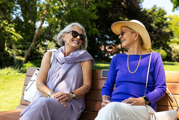 Two senior women enjoying a conversation on a park bench