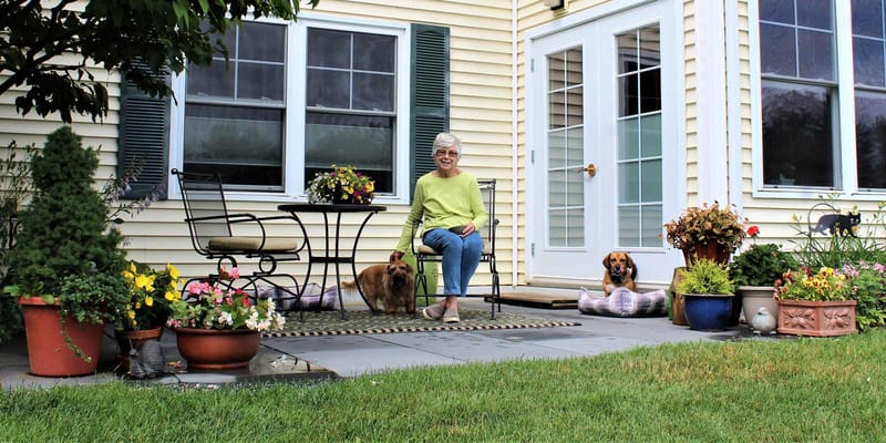 Resident enjoying time on a sunny outdoor patio with dogs