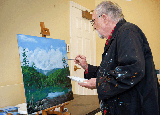 A resident painting in an indoor art class