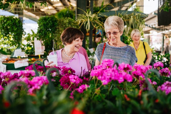 Two women enjoying flowers at a market