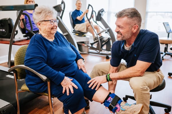 Senior resident interacting with a staff member in a fitness area