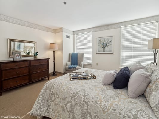 Well-decorated private resident room with a bed and seating area
