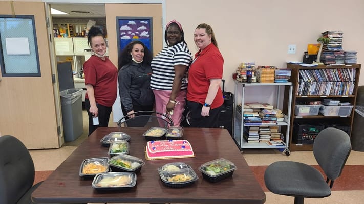 Staff celebrating with a resident over a decorated cake.