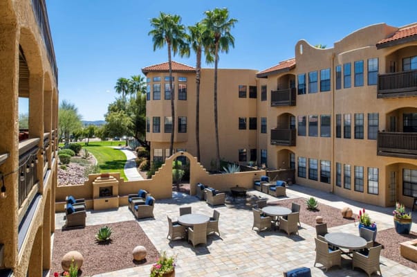 Outdoor courtyard with seating, palm trees, and Arizona landscape.
