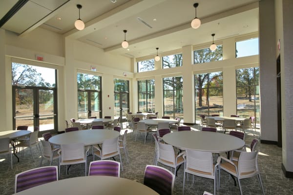 Bright community room with round tables and large windows