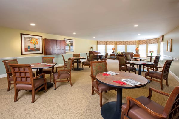 Spacious community room with tables and chairs at Benchmark Senior Living.