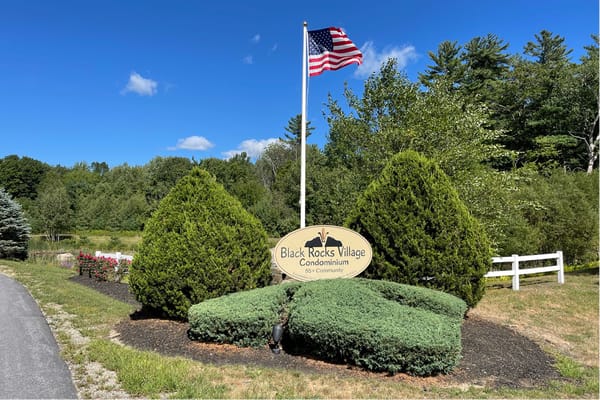 Sign for Black Rocks Village with American flag in background