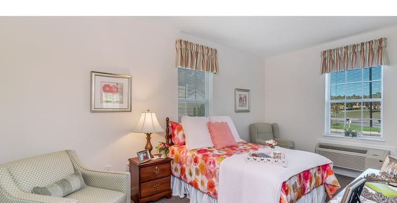 Bedroom with floral bedding, lamp, and armchair