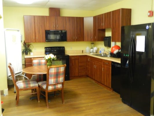 Kitchen area with wooden cabinets, black appliances, and a dining table.