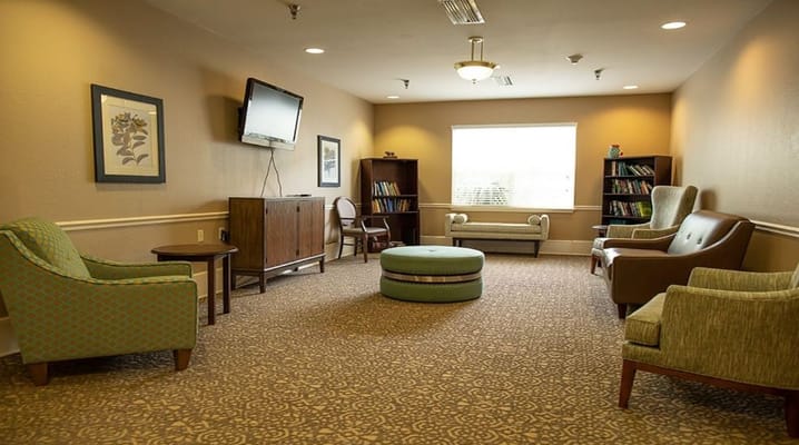 A cozy lounge area featuring seating, a coffee table, and bookshelves.