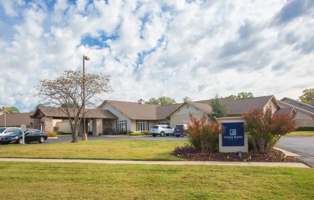 Exterior view of Cedar Ridge Senior Living facility with sign and parking area