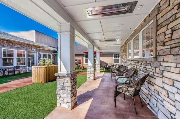 Covered outdoor seating area with chairs and greenery