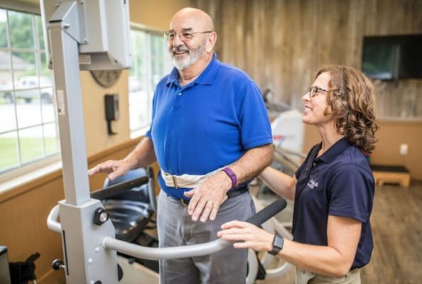 Therapist assisting a resident with physical therapy equipment