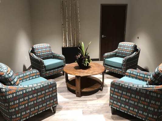 Cozy lounge area with patterned chairs and a wooden coffee table.