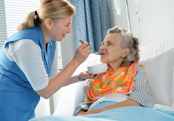 Caregiver feeding a resident in a cheerful room
