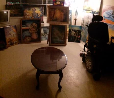 Wheelchair and wooden table in an art-filled room