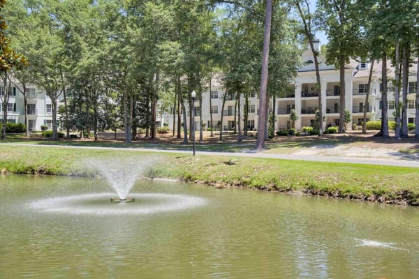 View of a serene pond with fountain and residential buildings