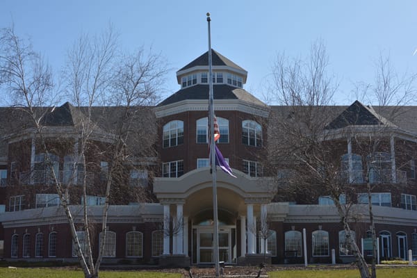 Front entrance of Holland Home Breton Woods with flags and trees
