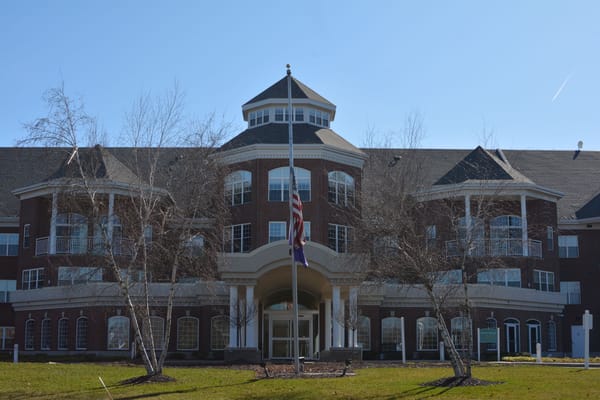 Main entrance of Holland Home Breton Woods with flagpole and trees