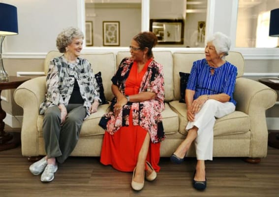 Three residents enjoying conversation in a cozy common area