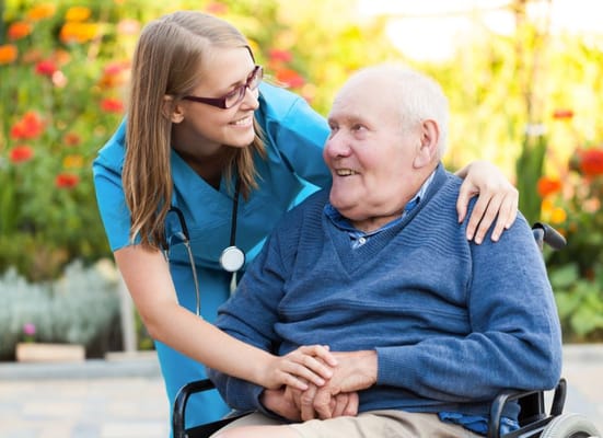 A caregiver smiling with a resident in a garden