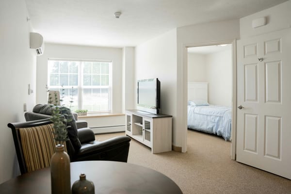 Living room space with a TV and view of a bedroom