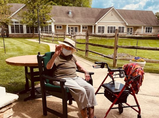 An elderly woman sitting in a garden area of the facility