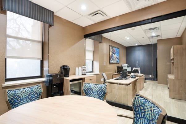 A well-lit office space with a round table and computer setup