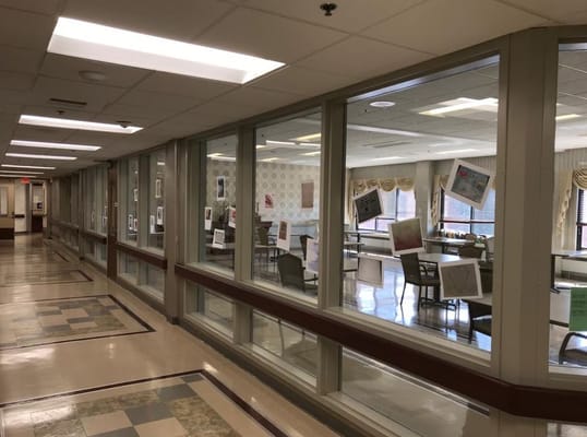 Interior hallway with windowed rooms showcasing artworks.