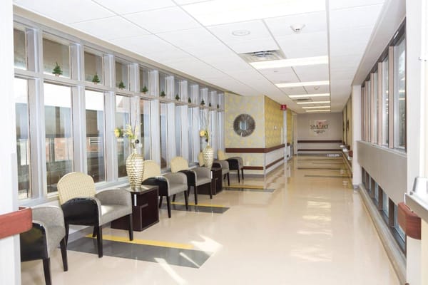 A well-lit hallway with seating and decorative elements at Hamilton Grove Healthcare.