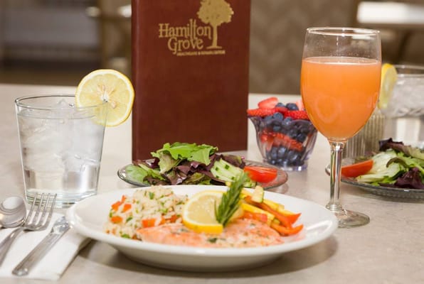 Plate of salmon, rice, and salad with a drink, set on a dining table