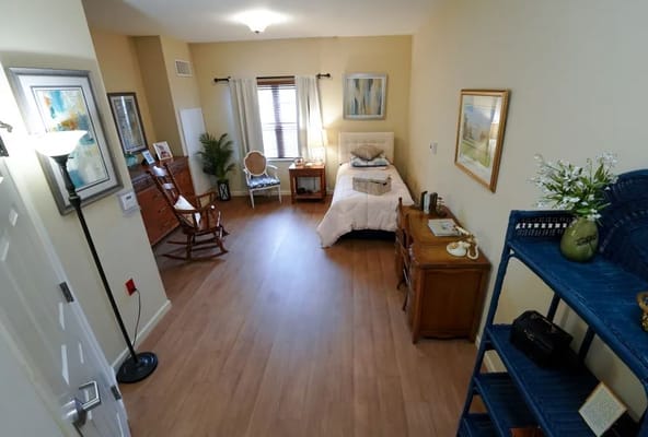 A cozy bedroom featuring a bed, rocking chair, and natural light.