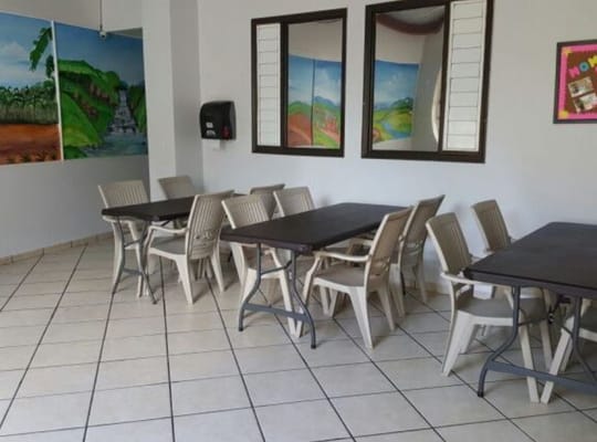 A dining area with multiple tables and chairs, decorated with colorful murals.