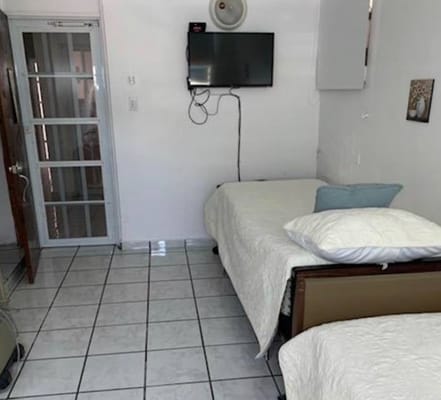Interior view of a shared room with two beds and a television.