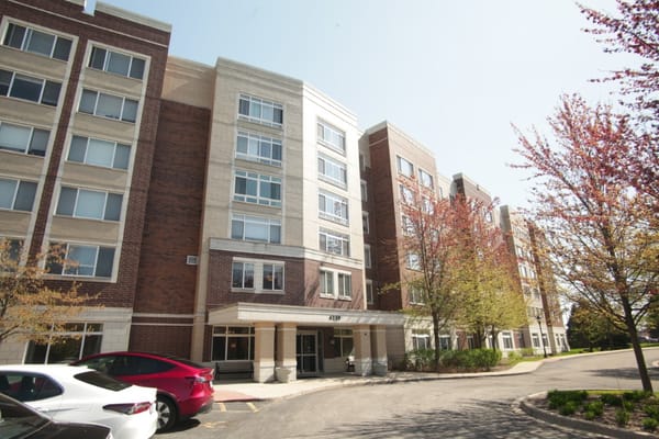 Front entrance of Autumn Green at Wright Campus with landscaping and vehicles in the parking lot.