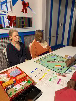 Two elderly residents playing Monopoly at a table during game night.
