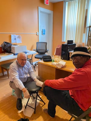 Caregiver providing foot care to a resident in a common area.