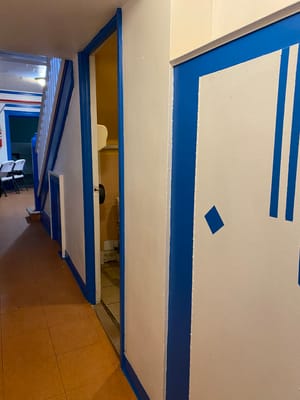 A hallway with blue trim and a doorway leading to a restroom