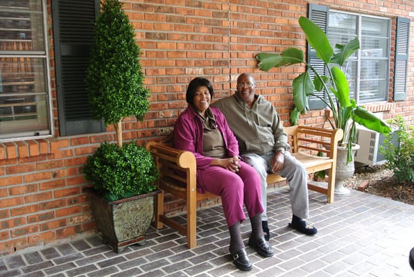 Two residents enjoying a sunny outdoor seating area