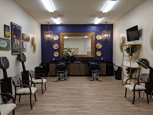Beauty salon area with chairs and a large mirror