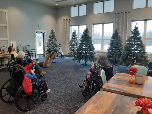 Residents in wheelchairs enjoying a decorated common area.