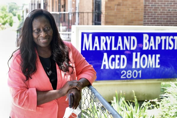 Staff member posing by the facility sign