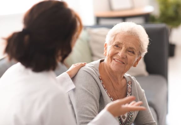 A caregiver talking with an elderly resident, both smiling.