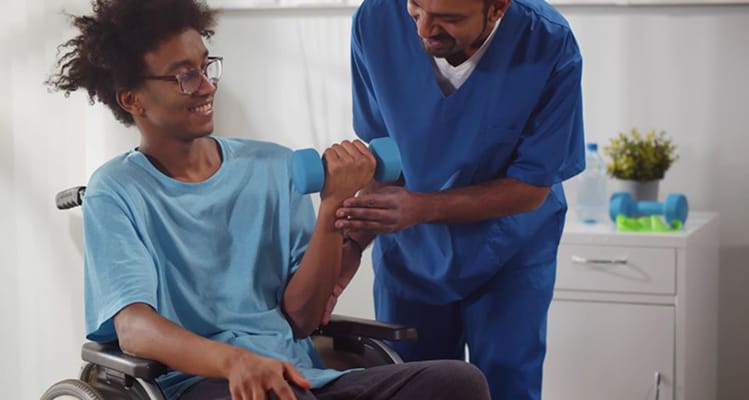 A staff member assisting a resident with weights in an exercise session