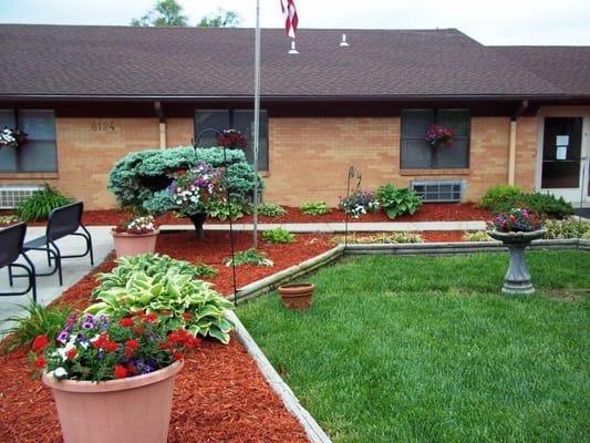 Garden area with colorful flowers and a flagpole in front of the building