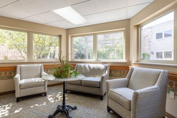 Lounge area with two armchairs and a small table surrounded by large windows.