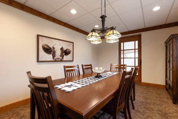 Dining room with a long wooden table and a cow painting on the wall