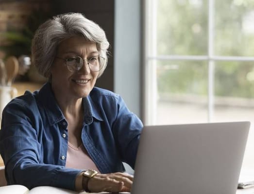 Senior woman smiling while using a laptop