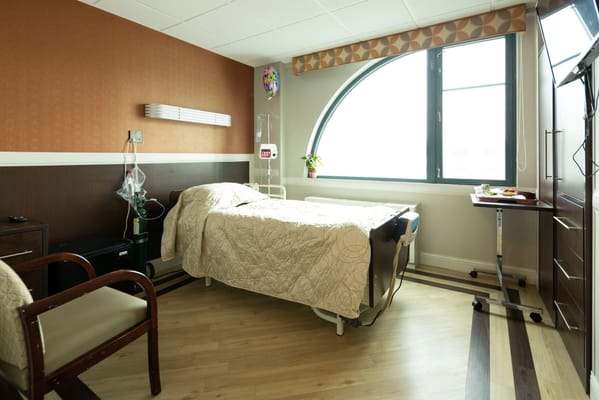 Cozy resident room featuring a bed, chair, and window at Seagate Rehabilitation and Nursing Center